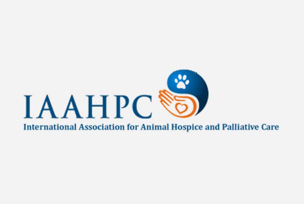 Logo for the International Association for Animal Hospice and Palliative Care (IAAHPC). It features two hands cradling a heart and a paw, symbolizing veterinary care and compassion, with the organization's acronym and full name beneath.